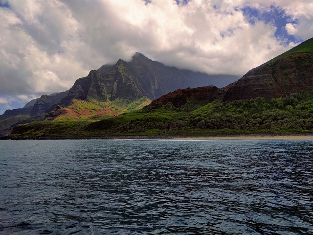 An image that showcases an aerial view of the majestic Hawaiian Islands, with crystal-clear turquoise waters and vibrant coral reefs surrounding the volcanic landscapes, portraying the diverse ecosystem and unique geological features